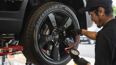 Photograph of a man changing a tire on a car.
