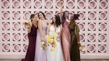 Four bridesmaids surround a bride in a white dress smiling and laughing.