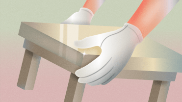 A worker with white gloves on lifts a table